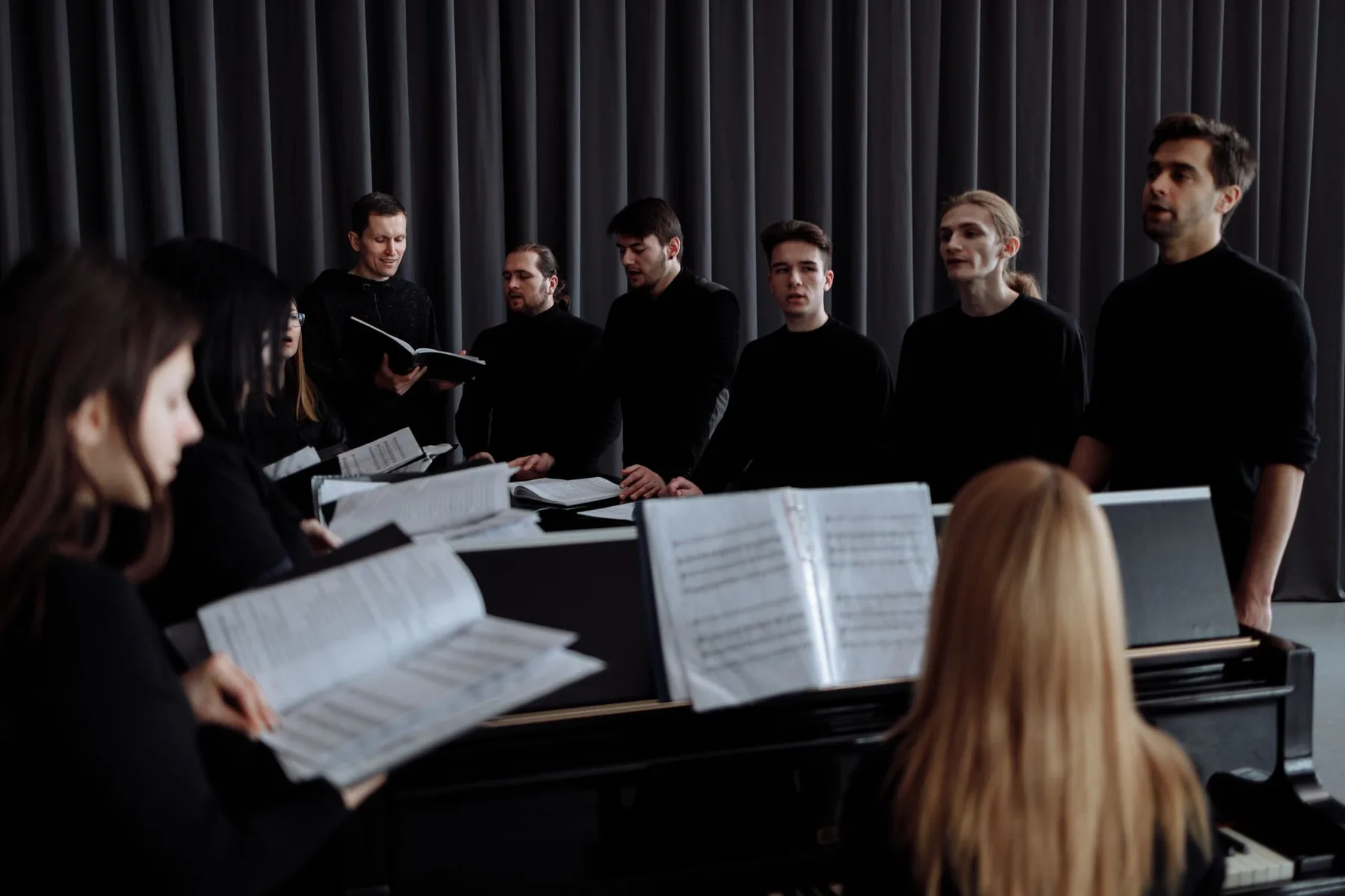 Choristers around the piano and sheet music Choristers around the piano and sheet music
